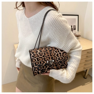 Detail of leopard print crossbody bag featuring a dark metal chain strap and lock