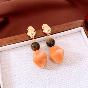 Detail view of tiger eye resin beaded earrings with irregular geometric golden metal design