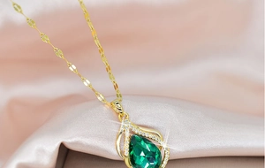 Detailed macro view of a golden teardrop pendant with a large green faceted gemstone