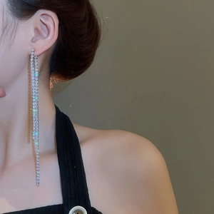 Detail of silver tassel earrings with zircon crystals worn by a model reaching the collarbone