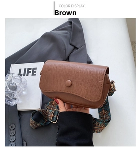 Close-up of brown pebbled leather crossbody bag with ethnic style woven wide strap