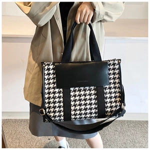 Detail of vintage houndstooth tote bag with leather flap held by a model in a studio