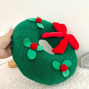 Detail of Christmas wreath plush pillow with red bow and berries in soft sherpa fabric