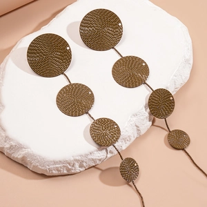 Detailed macro view of tiered olive green metal drop earrings with textured circular patterns