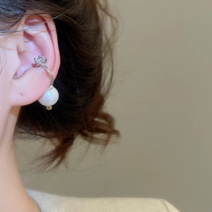 Detail of silver ear cuff with white pearl and sparkling zircon on a female ear
