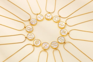 Macro shot of gold stainless steel zodiac necklaces with white pearl shell pendants