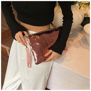 Close-up of rose gold sequin clutch bag with pink wrist strap and shiny metal zipper