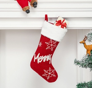 Detail of red plush Christmas stocking with white snowflake and Merry embroidery