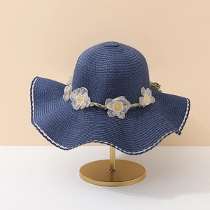 Détail du chapeau de paille bleu marine avec fleurs en tulle et bord en dentelle