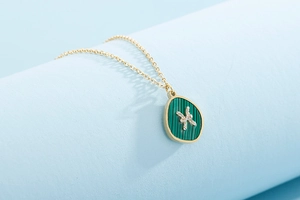 Macro side view of golden necklace featuring a drop-shaped green malachite Pisces pendant