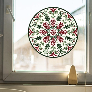 Detail of a red and green mandala snowflake window sticker on a glass surface