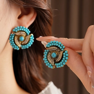 Vintage gold earrings with turquoise center and blue beads worn on a model's ear