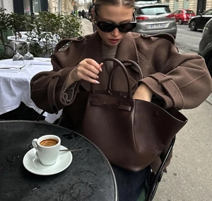 Détail du sac à main en cuir marron et du manteau en laine dans un café de rue