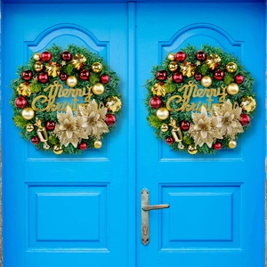 Christmas wreath with red and gold ornaments and Merry Christmas sign on a blue door