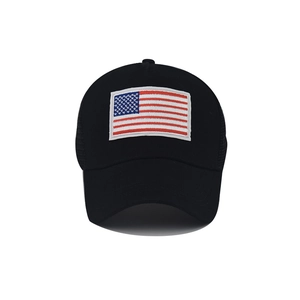 Detailed embroidery of the American flag on the front of a black mesh trucker cap