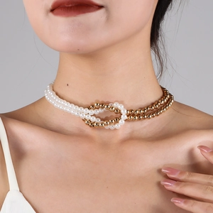 Detail of layered faux pearl and golden bead necklace worn on neck for fashion styling