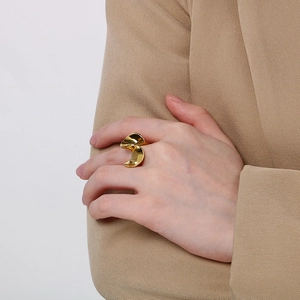 Detail of 18K gold plated wavy curve stainless steel ring worn on model hand with suit