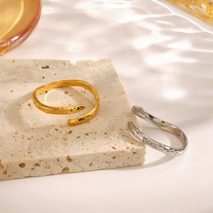 Minimalist gold and silver hammered texture open rings on a natural stone background