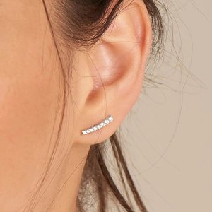 Macro shot of silver crescent pearl stud earring with sparkling zircons on model ear