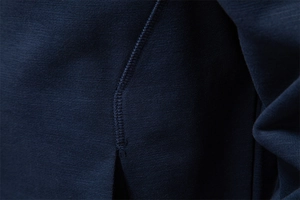 Macro shot of durable flatlock stitching on dark blue knitted men's baseball jacket