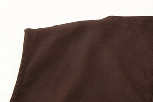 Close-up of deep brown woven fabric texture with detailed edge stitching on dress