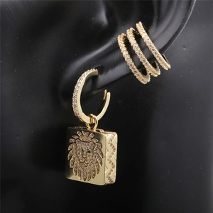 Macro shot of gold zircon geometric earrings and lion head pendant on black model ear