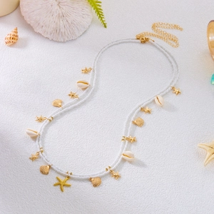 Macro detail of white beaded waist chain with golden starfish charms and natural seashells