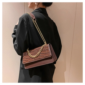 Détail du sac à bandoulière marron foncé effet crocodile avec chaîne dorée chic
