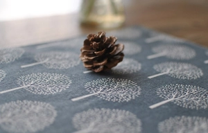 Close-up of grey-blue linen tea towel with white tree pattern and pine cone decor