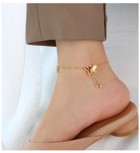 Close-up of a gold butterfly anklet with sparkling zircon tassels on a woman's ankle
