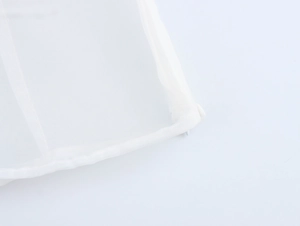 Detail view of an invisible zipper on a white sheer organza shirt with fine edge stitching