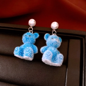 Detailopname van blauwe beer oorbellen met witte imitatieparels en flocking
