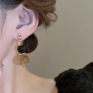 Nahaufnahme der Vintage-Resin-Ohrhänger mit Goldsteckern und bernsteinfarbenen Perlen