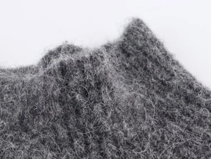 Macro view of dark grey wool blend fabric showing luxury beaded details and soft texture
