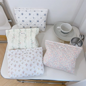 Collection of quilted floral cotton makeup bags in various pastel patterns on a white table