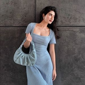 Détail de la robe bleu clair à col carré avec son sac à main plissé assorti élégant