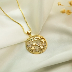Close-up of a gold MAMA pendant with tiny stars on soft fabric for Mother's Day