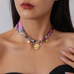 Detail of bohemian fabric choker featuring gold sunflower and clover charms on a model