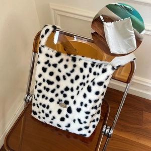 Close-up of reversible plush tote bag with cow print and canvas side on a chair