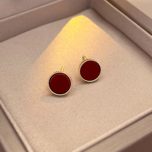 Vintage round stud earrings with deep red inlay and gold beaded edges on a jewelry box