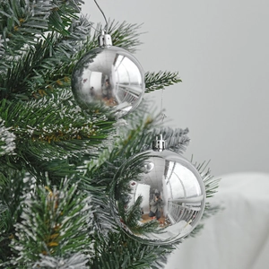 Glossy silver Christmas ornaments hanging on a green tree branch for holiday decor