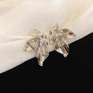 Macro detail of silver metal flower earrings with elegant tulle fabric background