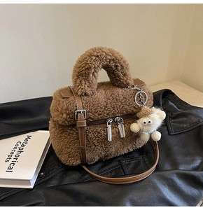 Detail of brown faux shearling handbag with leather straps and a white plush toy charm