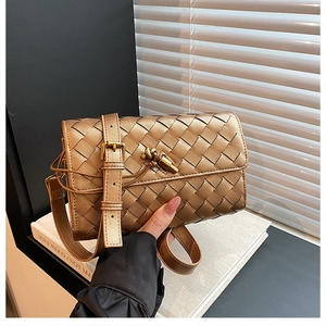 Detail of hand-woven crossbody bag with bronze leather texture and golden twist-lock closure