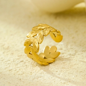 Macro view of gold plated leaf open ring with matte finish on sandy texture background