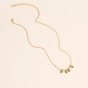 Detail of gold box chain necklace featuring turquoise evil eye beads and golden accents