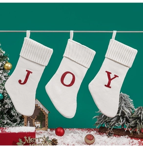 Detail of knitted Christmas stockings with JOY red letters on a festive green background