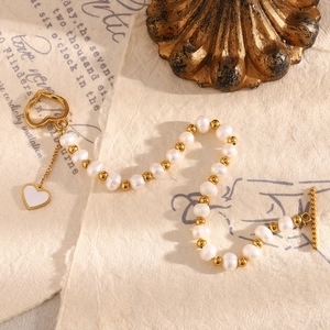 Detail of pearl bracelet with gold beads and heart charm on vintage paper backdrop