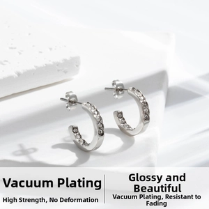 Detailed macro view of silver C-shape stainless steel earrings with sparkling zircon inlay