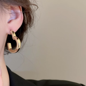 Gros plan sur une élégante boucle d'oreille dorée en forme de C avec fini métallique